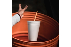Image A hand throwing away a cup into a trash can.